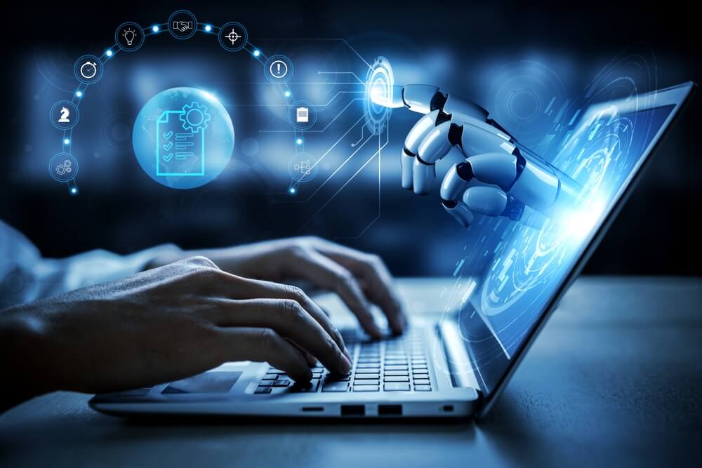 shutterstock_2706416959 mano robotica AI che esce dallo schermo di un laptop che sta usando un essere umano per rappresentare gli errori comuni che commettono le aziende quando usano le AI
