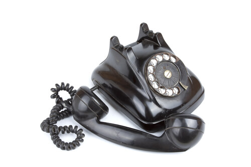 telefono fisso vecchio nero di bachelite con la cornetta arrotondata da cui è nata l'icona del chiamare al telefono