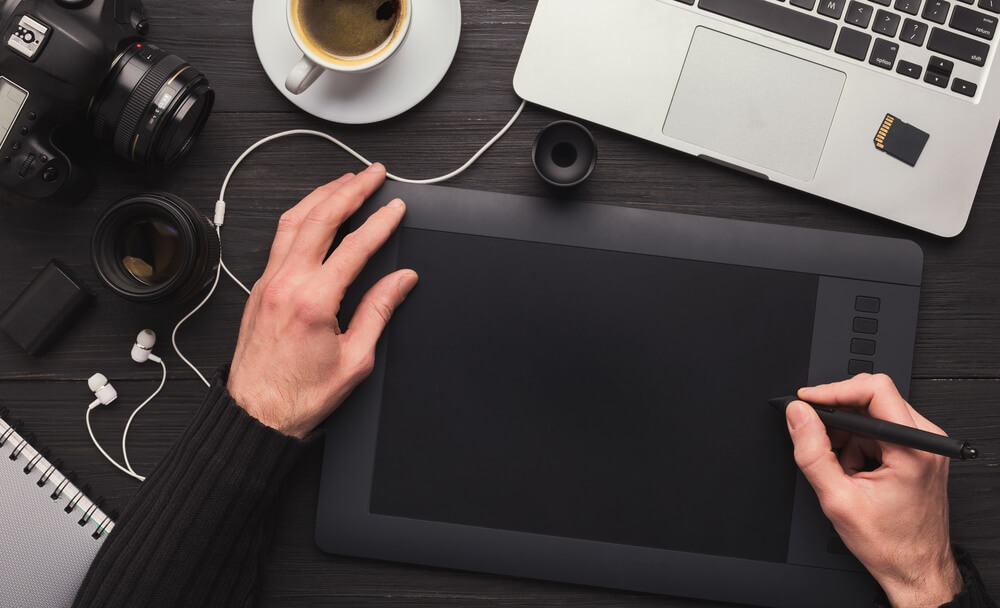 shutterstock_2760371145 graphic designer al lavoro con tablet e laptop per rappresentare cosa cercano i recruiter in un junior grpahic designer junior